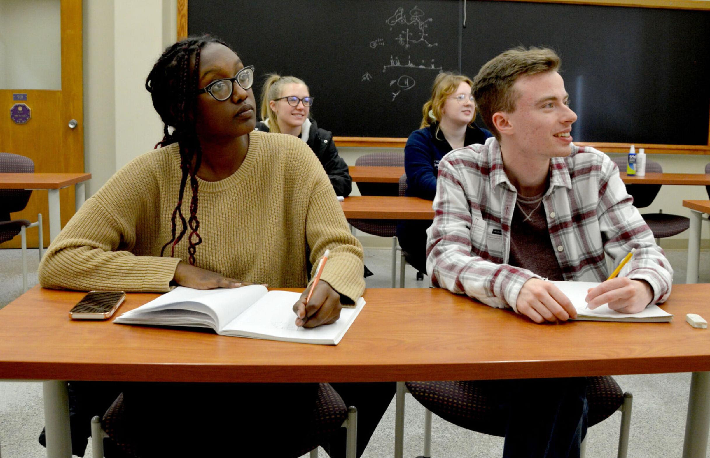 Four students listen and take notes during a Chemistry class